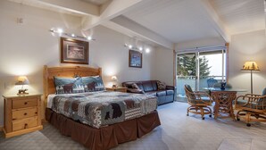 Une chambre à coucher avec un grand lit, une table de chevet en bois, une commode, un canapé et une table à manger avec des chaises.