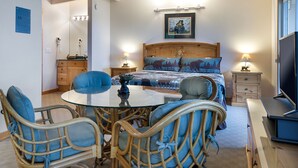 A bedroom with a bed, bedside tables, a TV, a chair, a table, and a mirror.