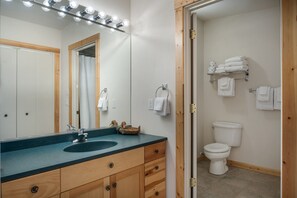 Une salle de bain avec un meuble-lavabo en bois, un évier, un miroir et des toilettes.