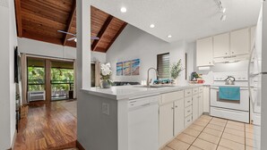 A modern kitchen with white cabinets, a built-in dishwasher, and a large island.