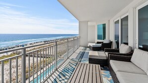 A balcony with wicker furniture, a view of the beach, and a pool. - Blu 501 ~ Luxury End-Unit w/3 Master Suites & Amazing Oceanfront Views ~ Sleeps 8 (Fort Walton Beach)