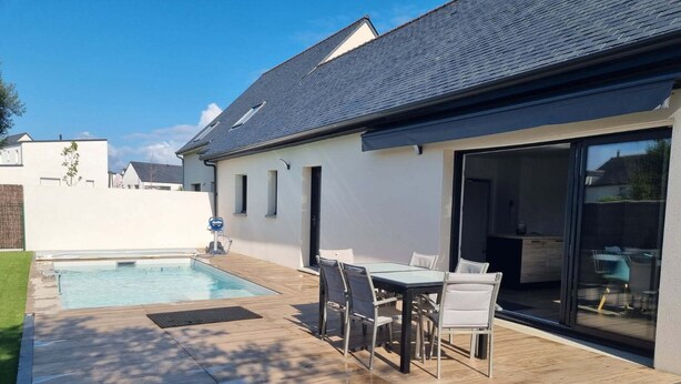 A modern house with a swimming pool, a patio with a table and chairs, and a sliding glass door leading to an indoor area. - House in Piriac Sur Mer ideal for spending time with family or friends. (Piriac-sur-Mer)