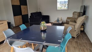 A modern dining area with a dark blue table, white and teal chairs, a glass terrarium, and wicker furniture. - House in Piriac Sur Mer ideal for spending time with family or friends. (Piriac-sur-Mer)