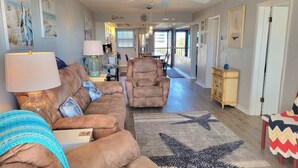 Un salon avec un canapé, un fauteuil et un tapis à motifs d’étoiles de mer.