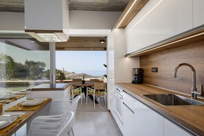 A modern kitchen with a wooden countertop, stainless steel sink, and white cabinetry.