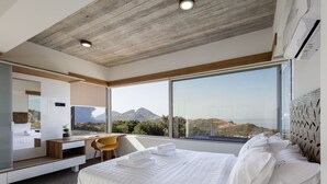 A modern bedroom with a large bed, a desk, and a view of mountains. - Seaview villa w/private pool, 4km to Plakias beach (Mariou)