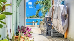 A narrow pathway leading to a beach with boats and palm trees.