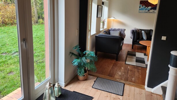 A modern living room with a black sofa, a small round table, and a potted plant. - Breakaway Cottage (Grasten)