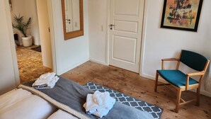 A room with a bed, a chair, a door, a mirror, and a painting on the wall. - Breakaway Cottage (Grasten)