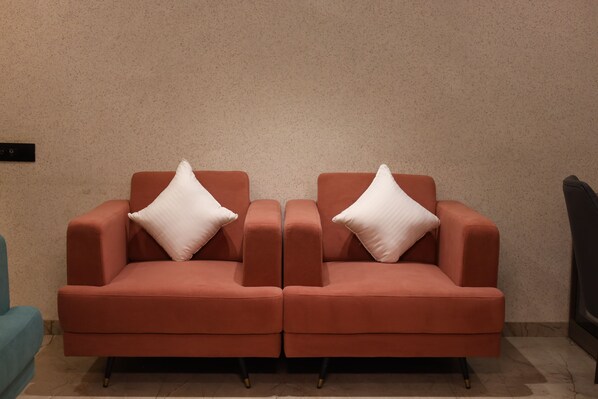 A red sofa with white cushions against a textured wall.