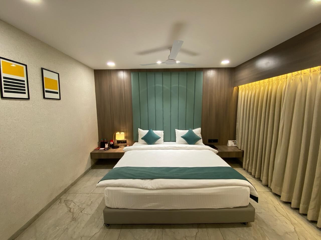 A modern hotel room with a large bed, a ceiling fan, and a nightstand with a lamp.