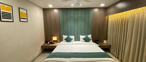 Una habitación de hotel moderna con una cama grande, un ventilador de techo y una mesita de noche con lámpara.