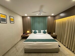 A modern hotel room with a large bed, a ceiling fan, and a nightstand with a lamp.