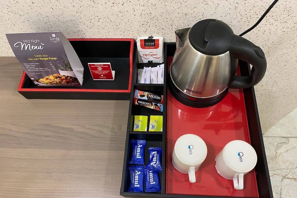 Un vassoio con un menù, bustine di tè, caffè istantaneo e due tazze.