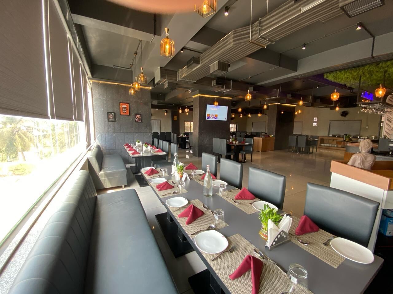 A restaurant with a long dining table set for a meal, surrounded by cushioned seating.