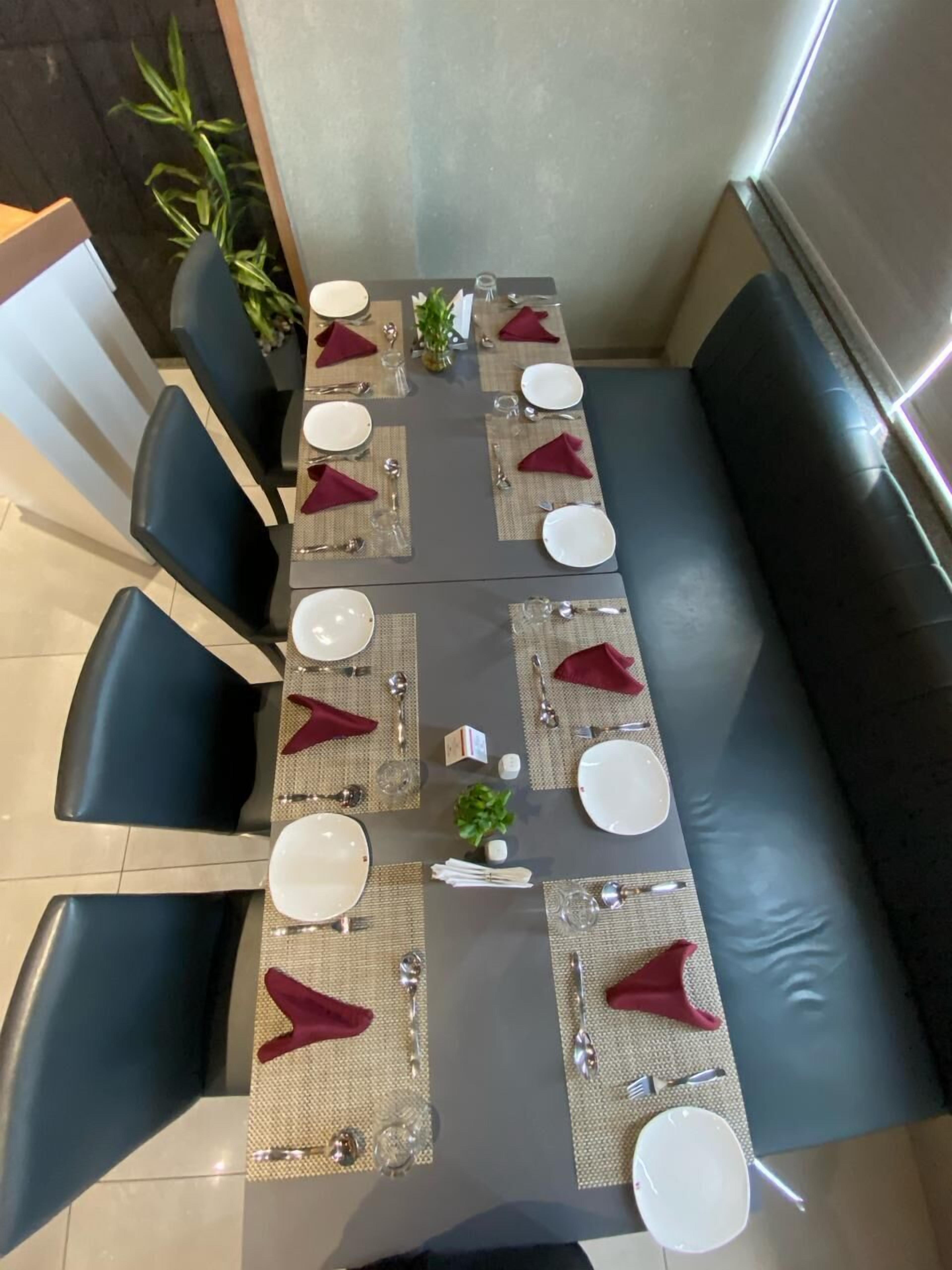 Comedor con una mesa larga dispuesta para varias personas, rodeada de sillas azul oscuro.