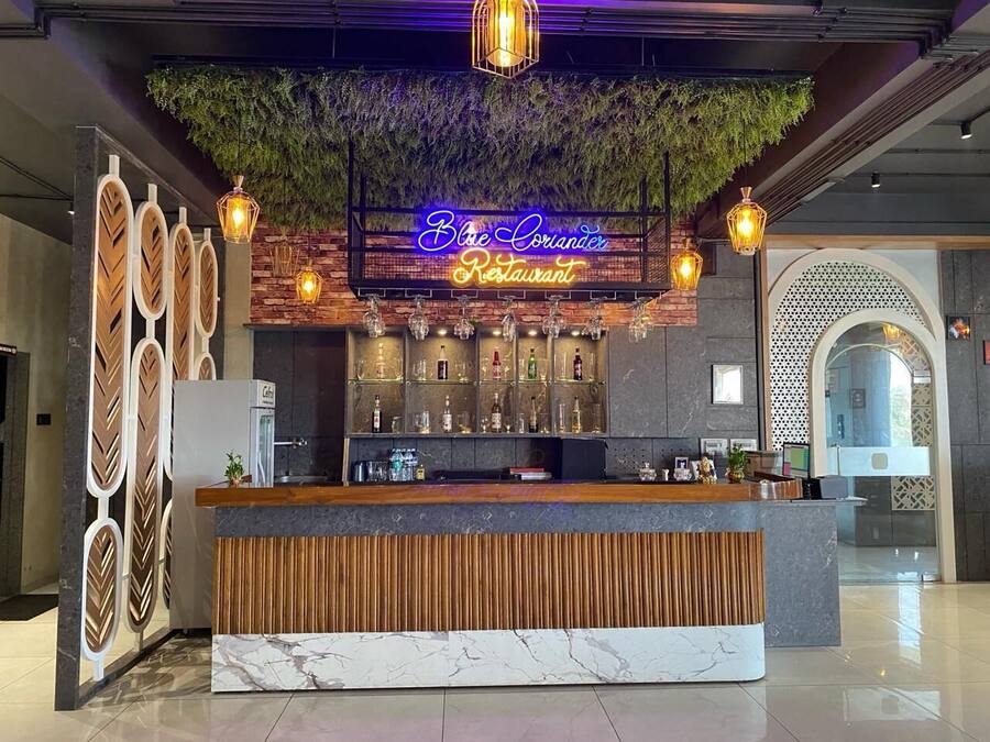 Un espace bar moderne, agrémenté d’un panneau néon, d’une décoration en bois et d’un comptoir d’accueil bien éclairé.