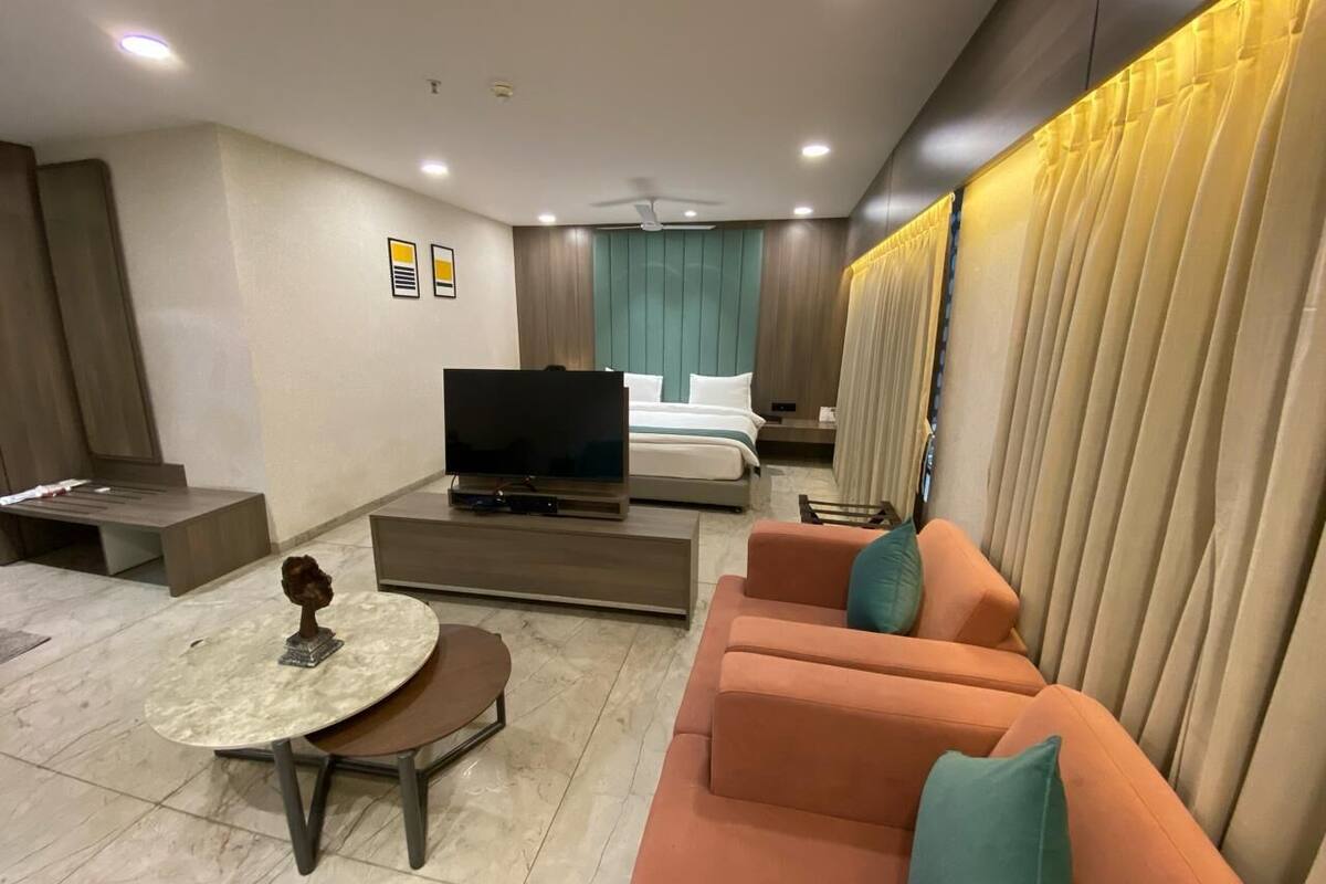 Una moderna camera d'albergo con divano, tavolino, televisore e letto.