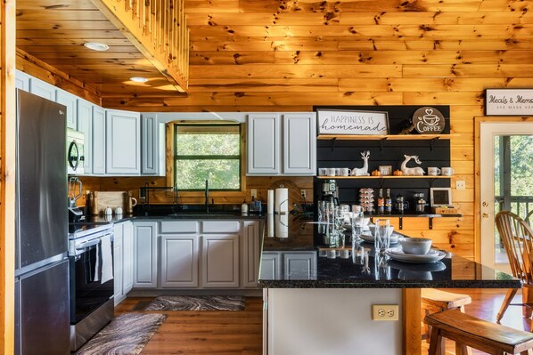 A modern kitchen with white cabinets, a stainless steel refrigerator, and a wooden ceiling. - Fire Pit*2 Hot Tubs*Basketball*Game Room*Mtn Views (Sevierville)