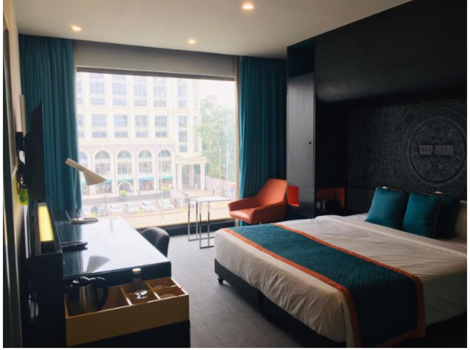 Habitación de hotel con cama, escritorio, silla y vista a un edificio.