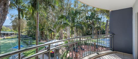 A balcony with a view of a tennis court and surrounding trees.
