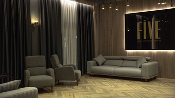 Un interior moderno con un sofá a cuadros, dos sillones y un suelo con estampado de espiga.
