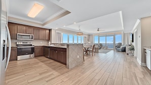 A spacious kitchen with modern appliances, a dining area with a view, and a balcony overlooking the ocean. - Beachfront 4BR Corner Unit!  Lazy River and Water Slide!! (Orange Beach)