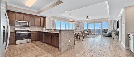 A spacious kitchen with modern appliances, a dining area with a view, and a balcony overlooking the ocean.