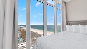 A hotel room with a large window offering a view of a beach and ocean. - Beachfront 4BR Corner Unit!  Lazy River and Water Slide!! (Orange Beach)