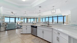 A modern kitchen with a dishwasher, a large island, and a view of the ocean.