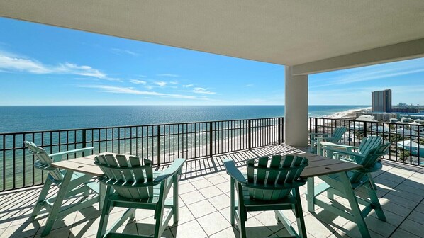 A balcony with a view of the ocean and beach, featuring a table and chairs. - 4BR Beachfront, Parking Level, Lazy River and Water Slide!! (Orange Beach)