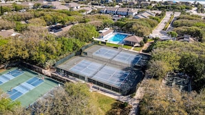 An aerial view of a residential area with a large swimming pool, tennis courts, and a beachfront. - Beachside Gem!  Sea Woods Condo 153 - Close to Pool & Beach Access (New Smyrna Beach)