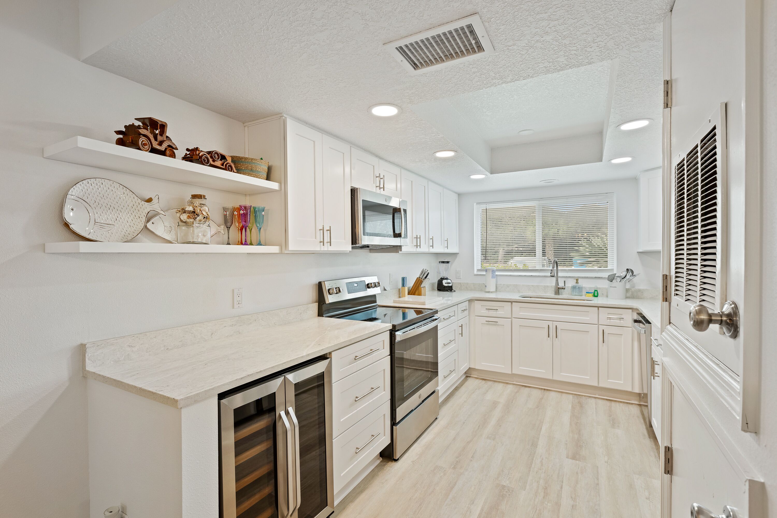 A modern kitchen with white cabinetry, stainless steel appliances, and a light wood floor.