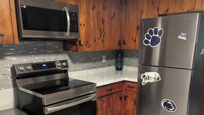 A kitchen with wooden cabinets, stainless steel appliances, and a marble countertop. - 2BR Sleeps 8 near Penn State, Stadium & Downtown with Hot Tub (State College)