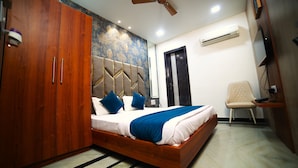 Een slaapkamer met een houten bed, een plafondventilator, een airconditioning en een stoel.