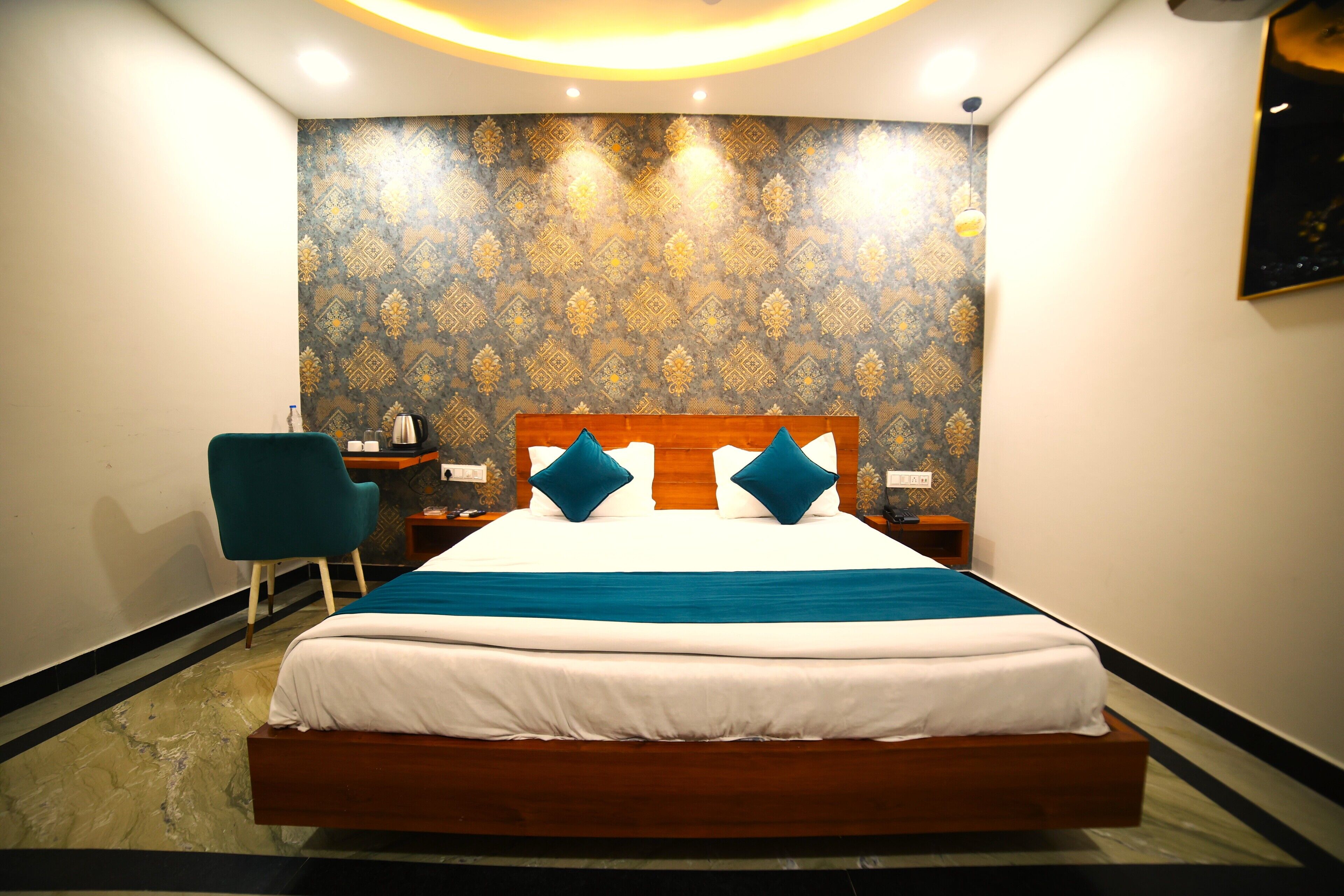 A neatly arranged hotel room with a large bed, a chair, a nightstand, and a wall with a patterned wallpaper.