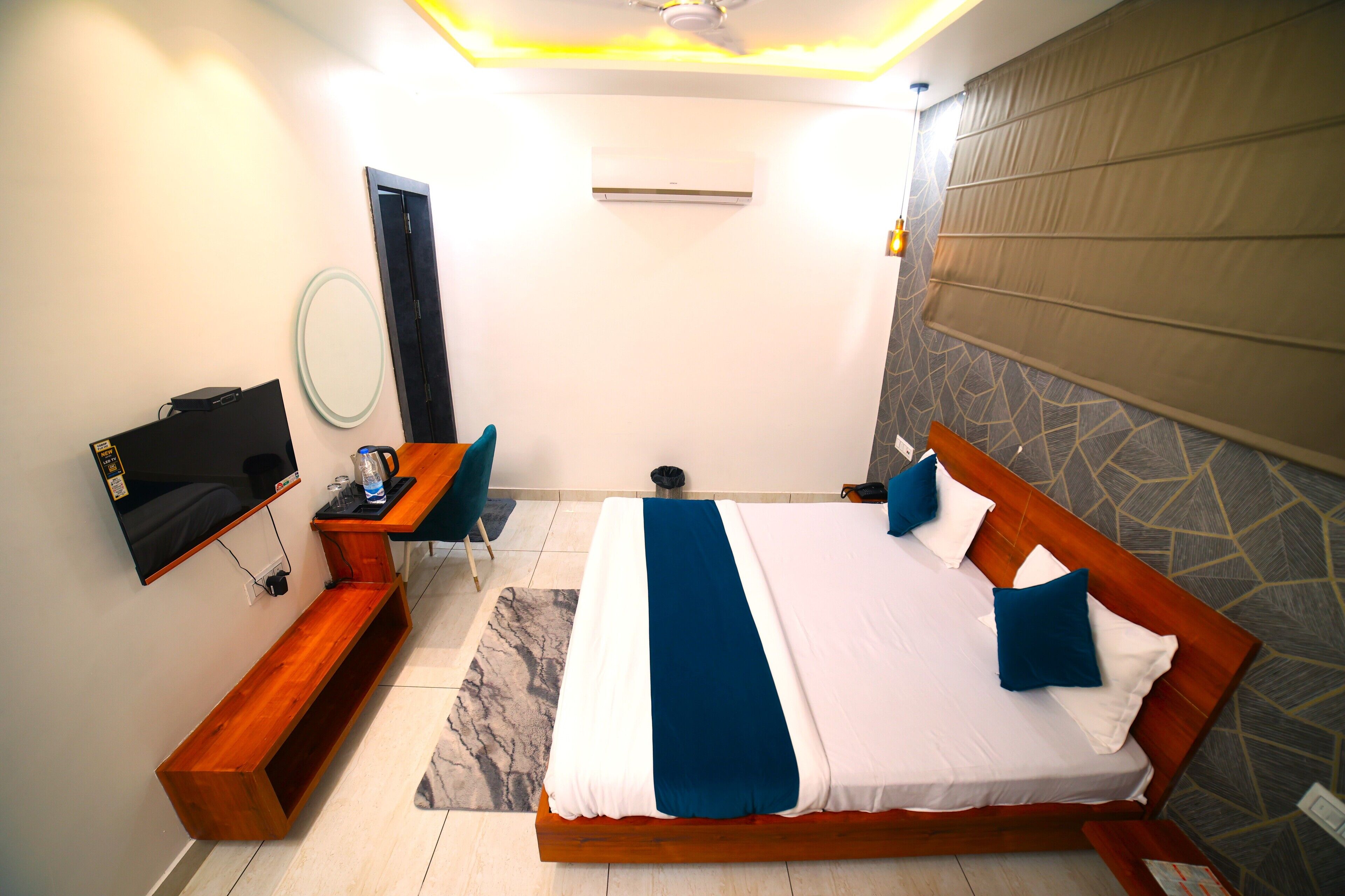 A modern hotel room with a large bed, a desk, a chair, a TV, and a bathroom.