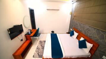 A modern hotel room with a large bed, a desk, a chair, a TV, and a bathroom.