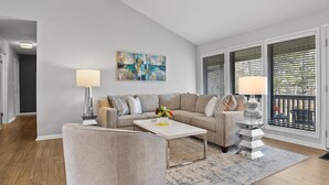 A modern living room with a beige sofa, a white coffee table, and a lamp. - Only two miles to UNC campus (Chapel Hill)