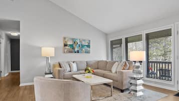 A modern living room with a beige sofa, a white coffee table, and a lamp.