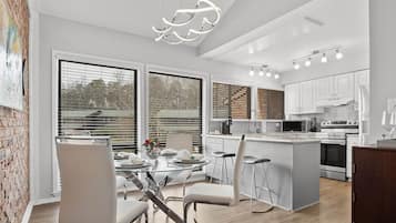 A modern kitchen with white cabinets, stainless steel appliances, and a central island.