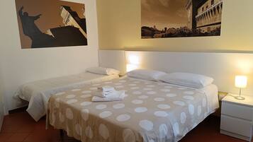 Habitación de hotel con dos camas, una mesita de noche y una lámpara de pared.