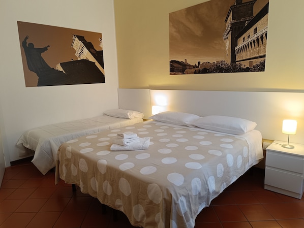 Habitación de hotel con dos camas, una mesita de noche y una lámpara de pared.
