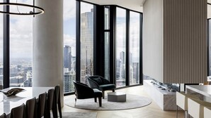 Ein modernes Wohnzimmer mit großem Fenster und Blick auf die Stadt, einem runden Couchtisch und einer Sitzecke mit Sofa und Sesseln.