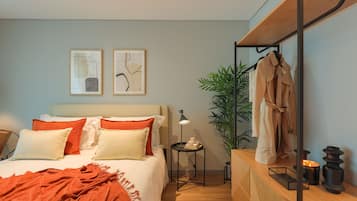 Une chambre à coucher moderne avec un lit, une table de chevet, une lampe et un miroir sur lequel est accroché un peignoir.