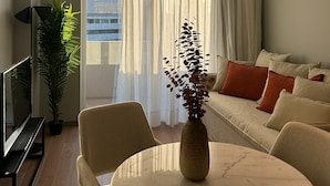 A modern living room with a sofa, a round table, a vase, and a potted plant. - Nôma Living Icon Apartments (Porto)