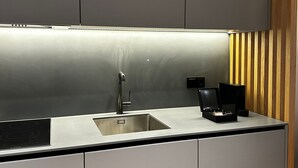 A modern kitchen with a stainless steel sink, a coffee maker, and a built-in oven. - Nôma Living Icon Apartments (Porto)