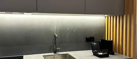 A modern kitchen with a stainless steel sink, a coffee maker, and a built-in oven.