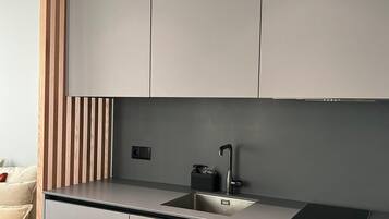 Eine moderne Küche mit grauen Schränken, einer schwarzen Arbeitsplatte, einem eingebauten Ofen und einem Spülbecken.