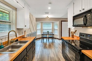 Una cocina moderna con suelo de madera, horno empotrado y comedor con mesa y sillas.